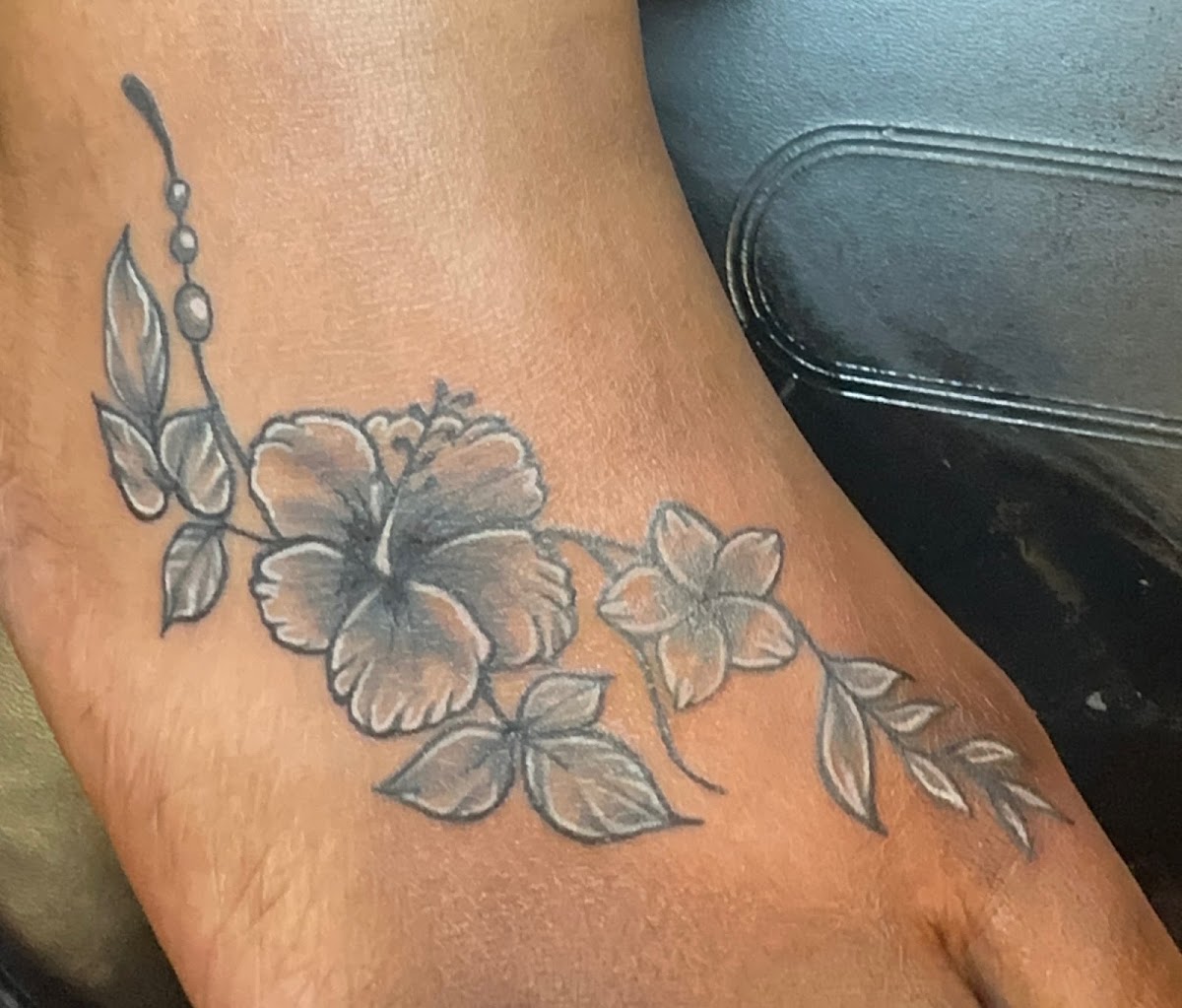 Grey wash hibiscus floral foot tattoo