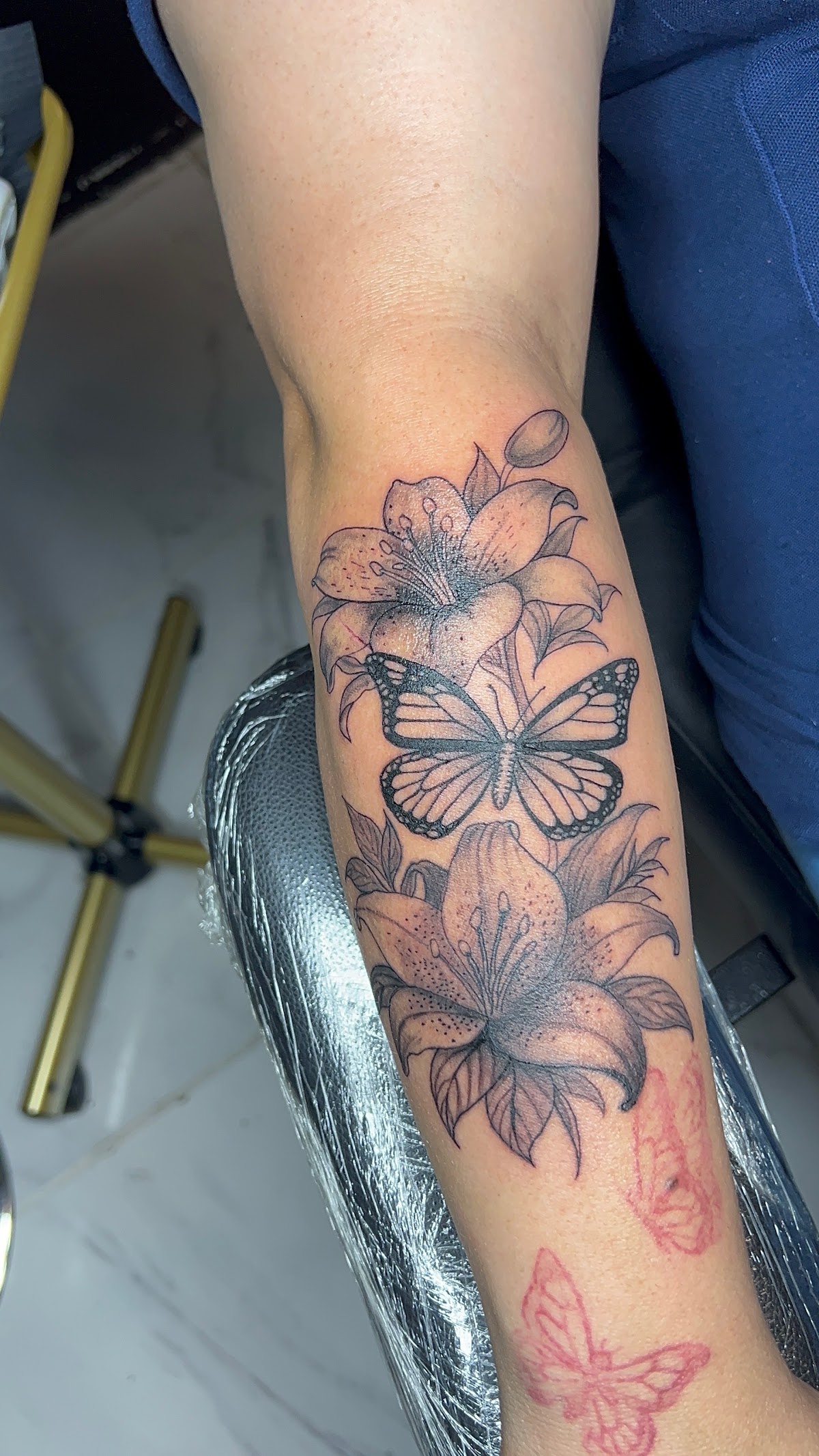 Butterfly and lily floral forearm tattoo in progress